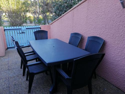 une table bleue et des chaises à côté d'un mur rose dans l'établissement Maison barcares, au Barcarès
