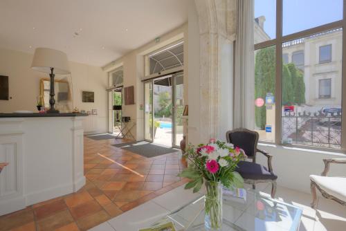 a living room with a vase of flowers on a table at Hotel Le Renoir in Sarlat-la-Canéda
