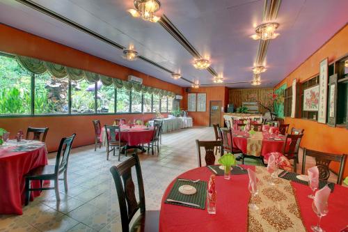 een restaurant met rode tafels en stoelen en ramen bij Honiara Hotel in Honiara