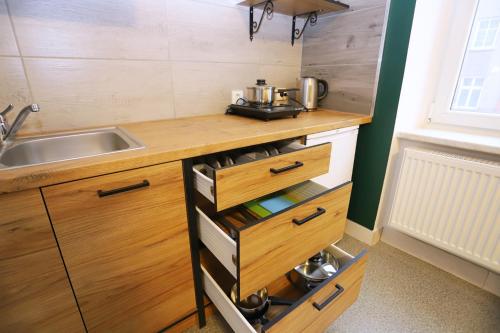 a kitchen with a sink and a counter with wooden cabinets at Noclegi Pan Tadeusz in Wałbrzych