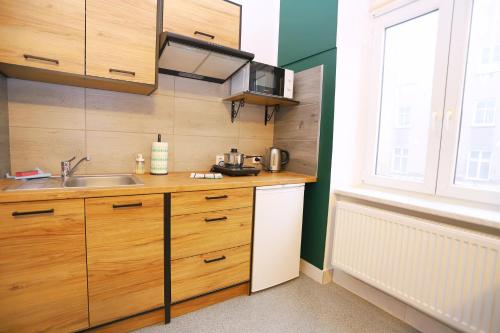 a kitchen with wooden cabinets and a sink and a window at Noclegi Pan Tadeusz in Wałbrzych