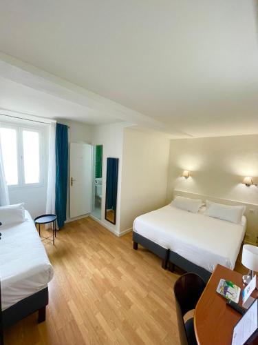 a hotel room with two beds and a table at Hôtel Posta Vecchia in Bastia