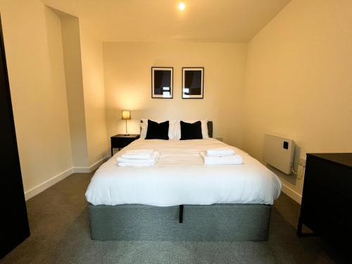 um quarto com uma grande cama branca e 2 almofadas em Fantastic one bedroom apartment near Old Trafford Stadium em Manchester