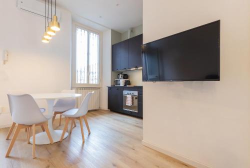 a dining room with a table and chairs and a television on a wall at Milan Retreats in Milan