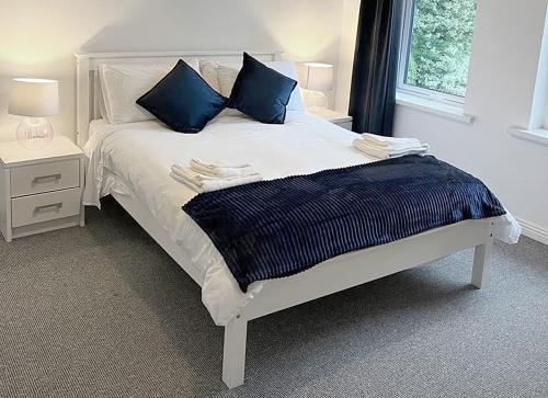 - un lit blanc avec des oreillers bleus dans une chambre dans l'établissement Burren Seaside Lodge, à Ballyvaughan