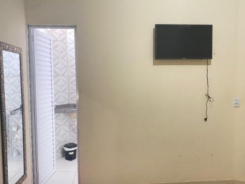 Une télévision à écran plat est installée sur un mur à côté d'une porte. dans l'établissement Pousada Mineira, à Barreirinhas