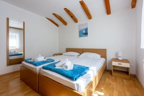 a bedroom with two beds with blue towels on them at Apartments NEVEN in Grižane