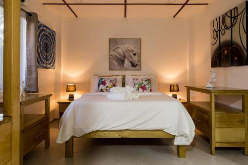 Schlafzimmer mit einem Bett mit weißer Bettwäsche und Kissen in der Unterkunft Alona Apartments in Panglao