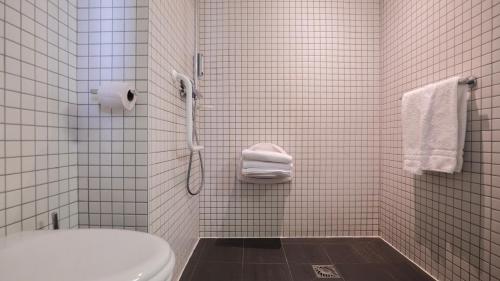a white tiled bathroom with a toilet and a shower at Le Faucigny - Hotel de Charme & SPA in Chamonix-Mont-Blanc