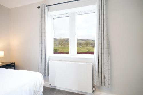 a bedroom with a bed and a window with a view at Cheshire Mews in Castleton
