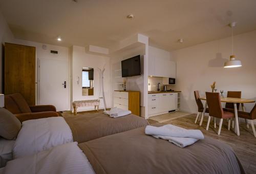 a room with two beds and a table and a kitchen at APARTHOTEL Wałcz in Wałcz