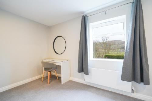Zimmer mit einem Fenster, einem Schreibtisch und einem Spiegel in der Unterkunft Cheshire Mews in Castleton