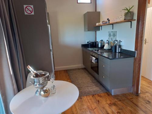 a kitchen with a white table and a refrigerator at Forest Valley Cottages in Knysna