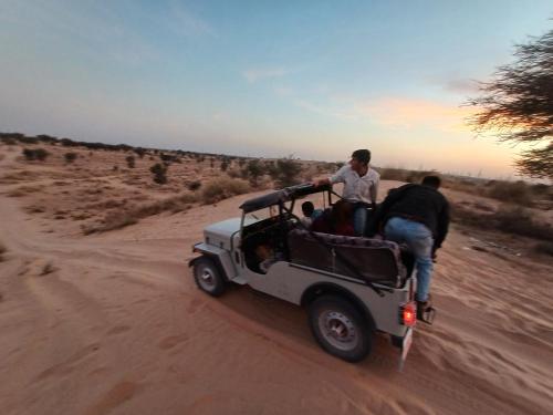 two men in a jeep driving in the desert at Bikaner Desert Camp and Resort in Bikaner