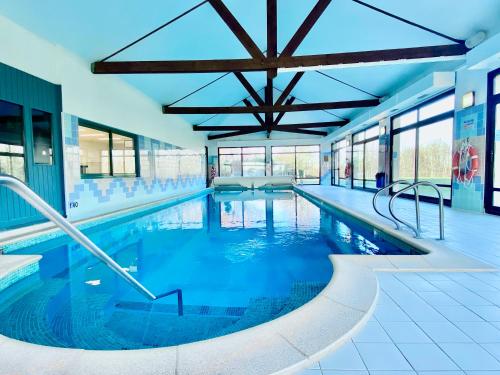 a large swimming pool with blue water in a building at Holiday Inn Calais Coquelles, an IHG Hotel in Coquelles