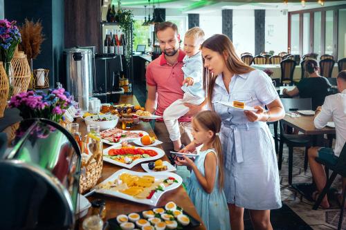 een groep mensen die rond een tafel met eten staan bij Zacisze Nad Nidą Resort in Pińczów
