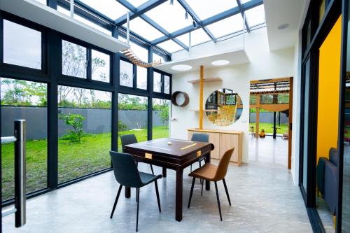 a dining room with a table and chairs and large windows at 和你民宿 in Xincheng