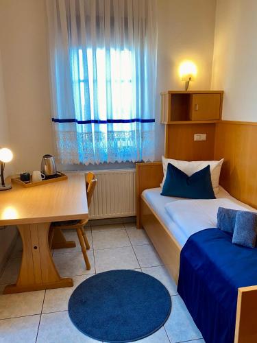 a small room with a bed and a table and a desk at Hotel La Ferté in Stuttgart