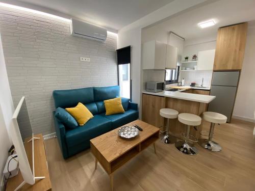 sala de estar con sofá azul y cocina en Lovely Private Suite Center, en Málaga