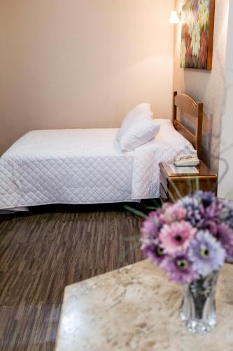 a bedroom with a bed and a vase of flowers on a table at Pousada Sossego da Pampulha in Belo Horizonte