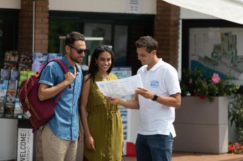 a group of three people looking at a piece of paper at Campeggio Europa Silvella in San Felice del Benaco