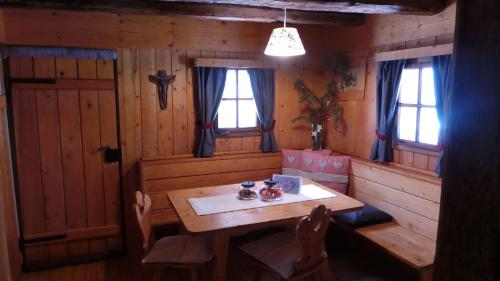 ein Esszimmer mit einem Holztisch und 2 Fenstern in der Unterkunft Chalet Wildgall in Anterselva di Mezzo