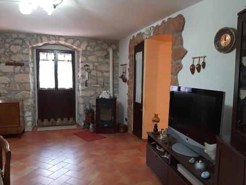 ein Wohnzimmer mit einem TV und einer Steinmauer in der Unterkunft Nel cuore della maiella in Palombaro