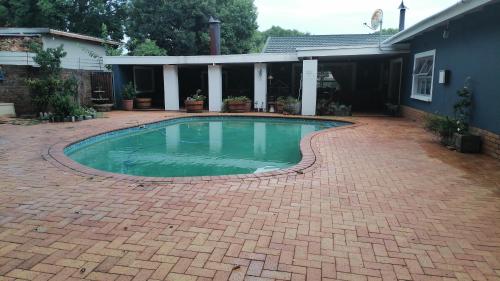 a swimming pool on a brick patio in front of a house at The Marilyn Room in Centurion