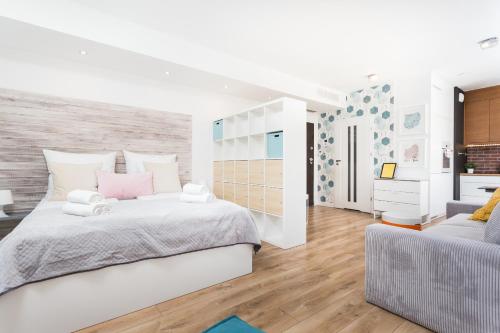 a white bedroom with a large bed and a couch at InPoint Central Apartments in Kraków