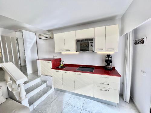a kitchen with white cabinets and a red counter top at Beachhouse La Palma in Costa Calma