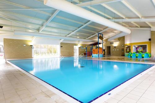 a swimming pool with blue water in a large room at Camping Pods Sand Le Mere in Tunstall