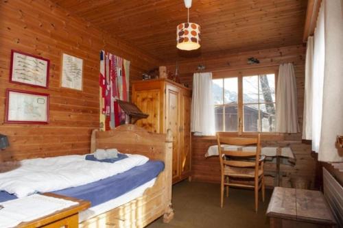 a bedroom with a bed and a table in a cabin at Ferienhaus Roth Flüehli, Hasliberg Goldern, 9-Betten in Hasliberg