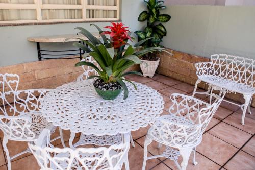 a white table and chairs with a red flower on it at Pousada Sossego da Pampulha in Belo Horizonte