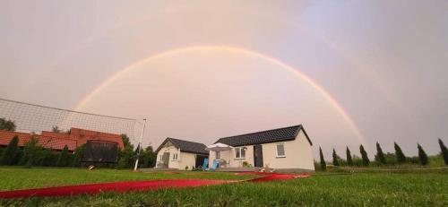 a rainbow in the sky over a house at Bajkowe Domki Marzeń Krecik in Węgorzewo