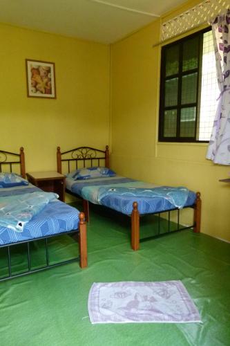a room with two beds and a window at Cheers Garden Chalet in Kampung Tekek