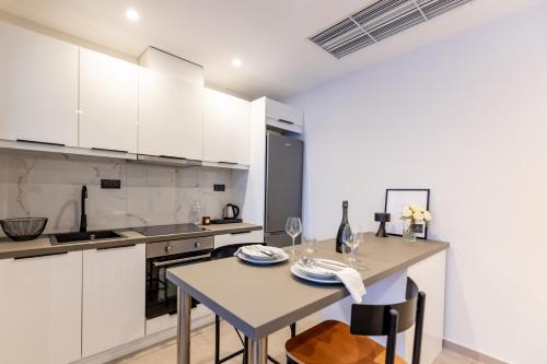 a kitchen with white cabinets and a table and chairs at Kaleo Chios Luxury Apartments in Chios