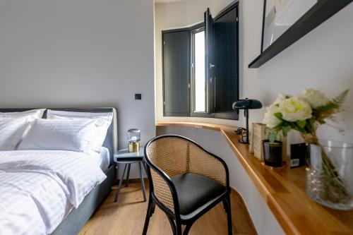 a bedroom with a bed and a chair and a window at Kaleo Chios Luxury Apartments in Chios