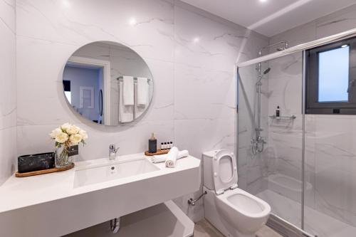 a bathroom with a sink and a toilet and a mirror at Kaleo Chios Luxury Apartments in Chios