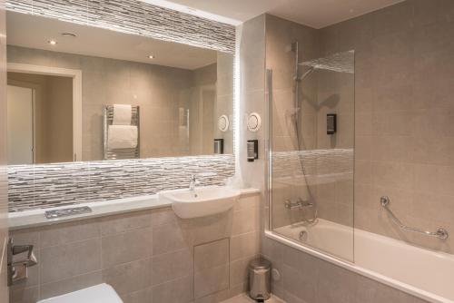 uma casa de banho com um lavatório, um chuveiro e um espelho. em PREMIER SUITES PLUS Glasgow Bath Street em Glasgow