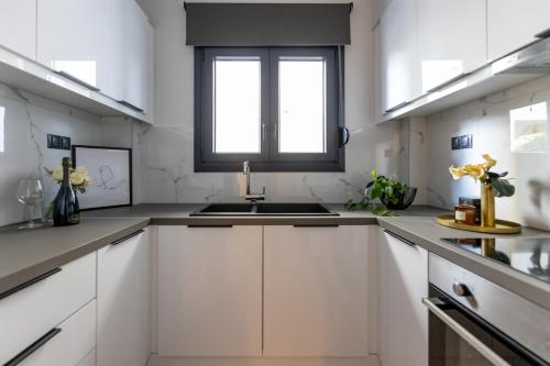 a white kitchen with a sink and a window at Kaleo Chios Luxury Apartments in Chios