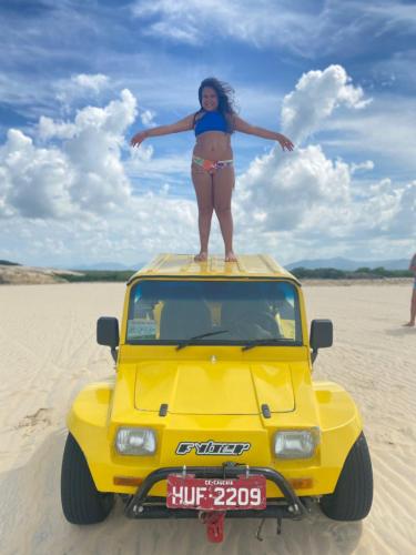 a woman standing on top of a car on the beach at CUMBUCO - Eco Paradise - AP 112 in Caucaia