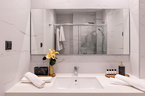 a white bathroom with a sink and a mirror at Kaleo Chios Luxury Apartments in Chios