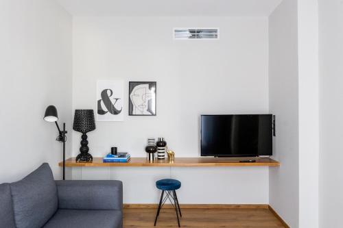 a living room with a couch and a tv on a shelf at Kaleo Chios Luxury Apartments in Chios