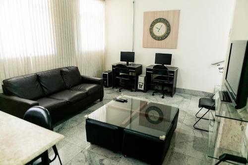 a living room with a couch and a clock on the wall at Pousada Sossego da Pampulha in Belo Horizonte