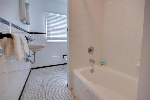 a white bathroom with a tub and a sink at Empress Motel in Ocean City