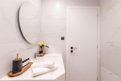 a white bathroom with a mirror and a sink at Kaleo Chios Luxury Apartments in Chios