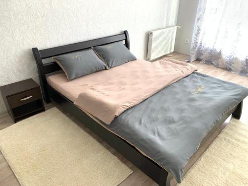 a bed with a black headboard and pillows on it at Комфортна квартира. Поруч парк in Ternopilʼ