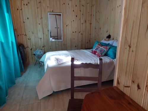 ein Schlafzimmer mit einem Bett in einem Holzzimmer in der Unterkunft Cabaña Azul in San Martín de los Andes