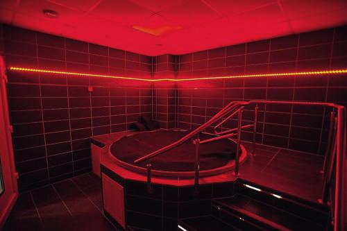 a red room with a tub in a tiled bathroom at Hotel Aldo in Uničov
