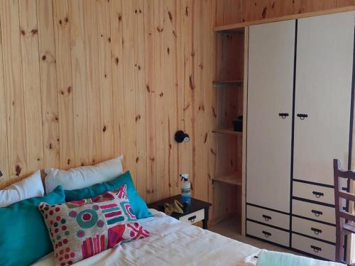 1 dormitorio con 1 cama y pared de madera en Cabaña Azul en San Martín de los Andes